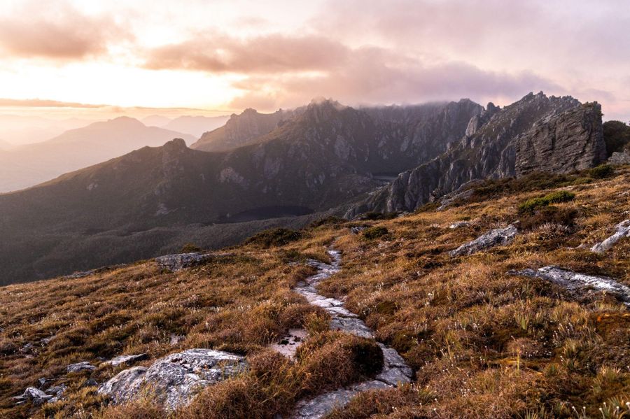 A walking track leading through mountains at sunrise